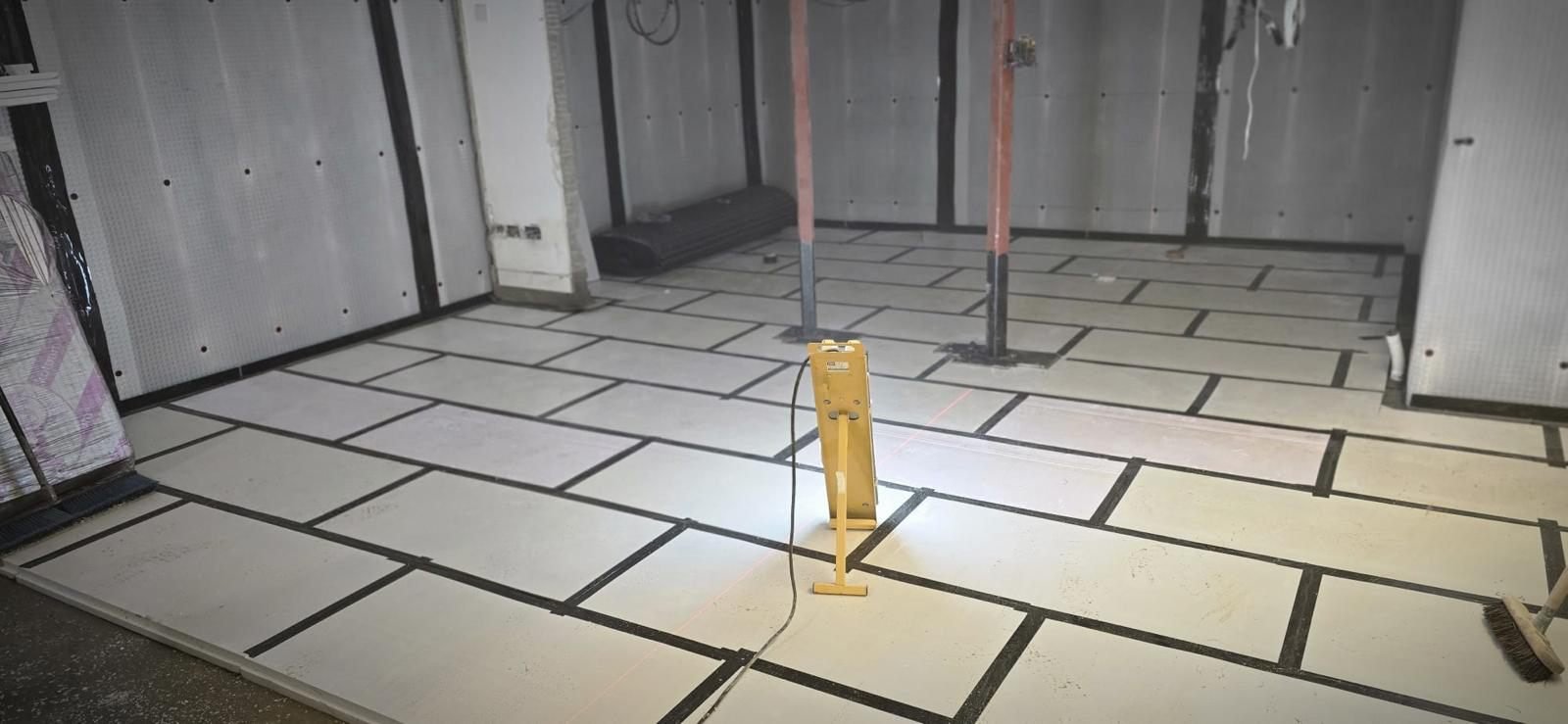 A basement floor build-up over cavity drain membrane, with levels being set using a laser level