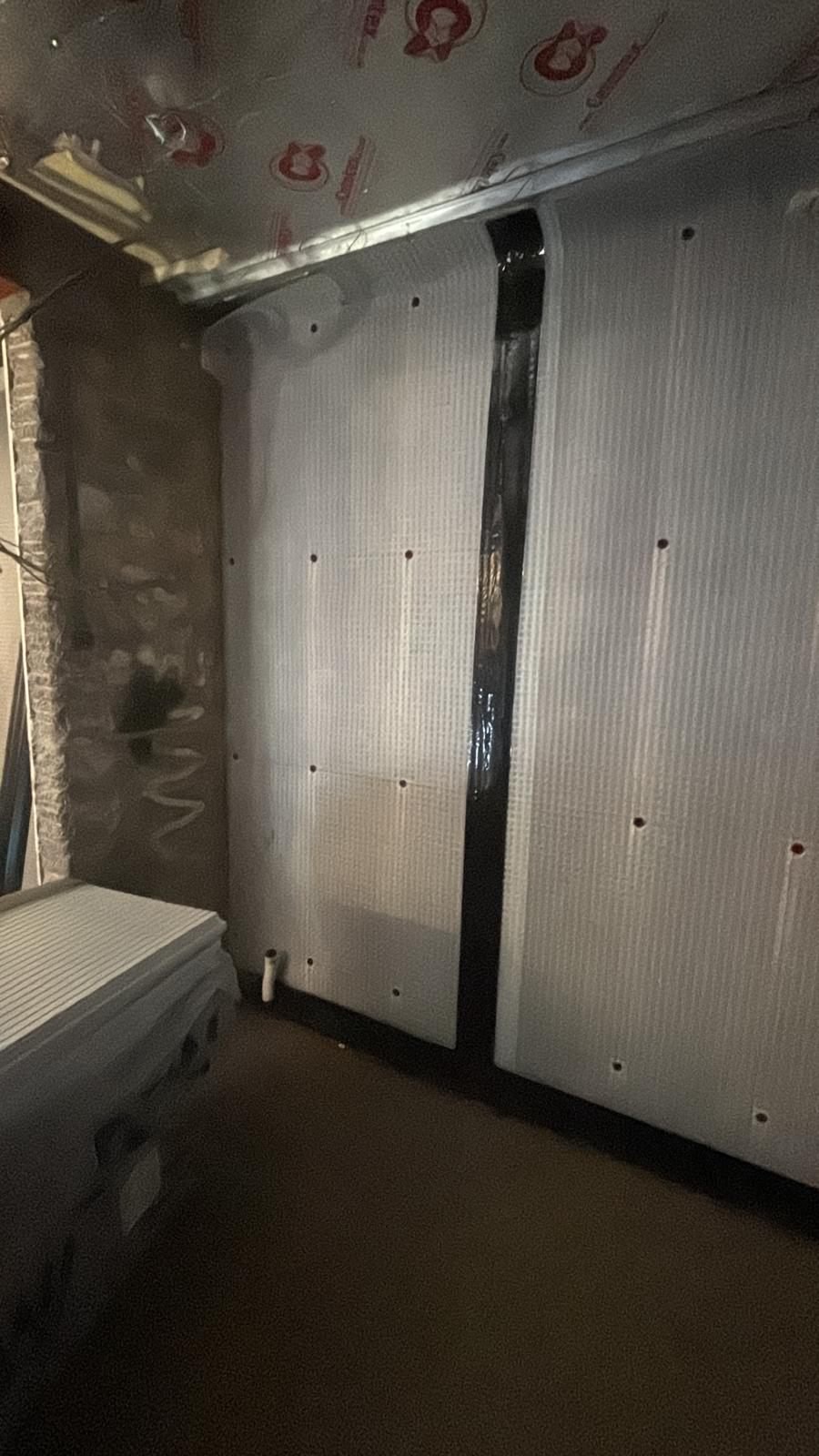Cavity drain membrane fixed to a basement wall with sealed plugs, with the joint between two sheets sealed with tape
